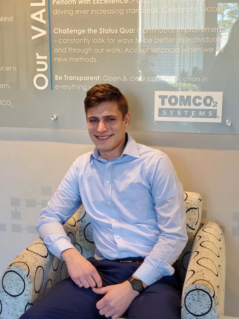 Bradley Krahn pictured in front of the TOMCO Systems logo